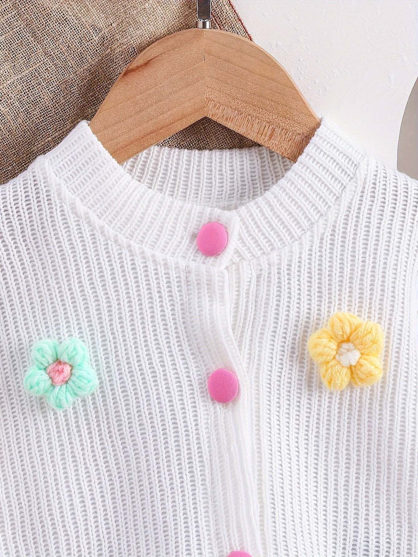 Adorable girls' outfit with cute floral appliques on a white knitted top.