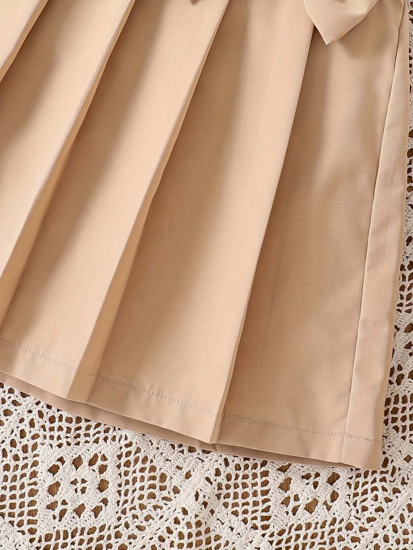 Chic girls' pleated sweatshirt dress in beige fabric on lace background.