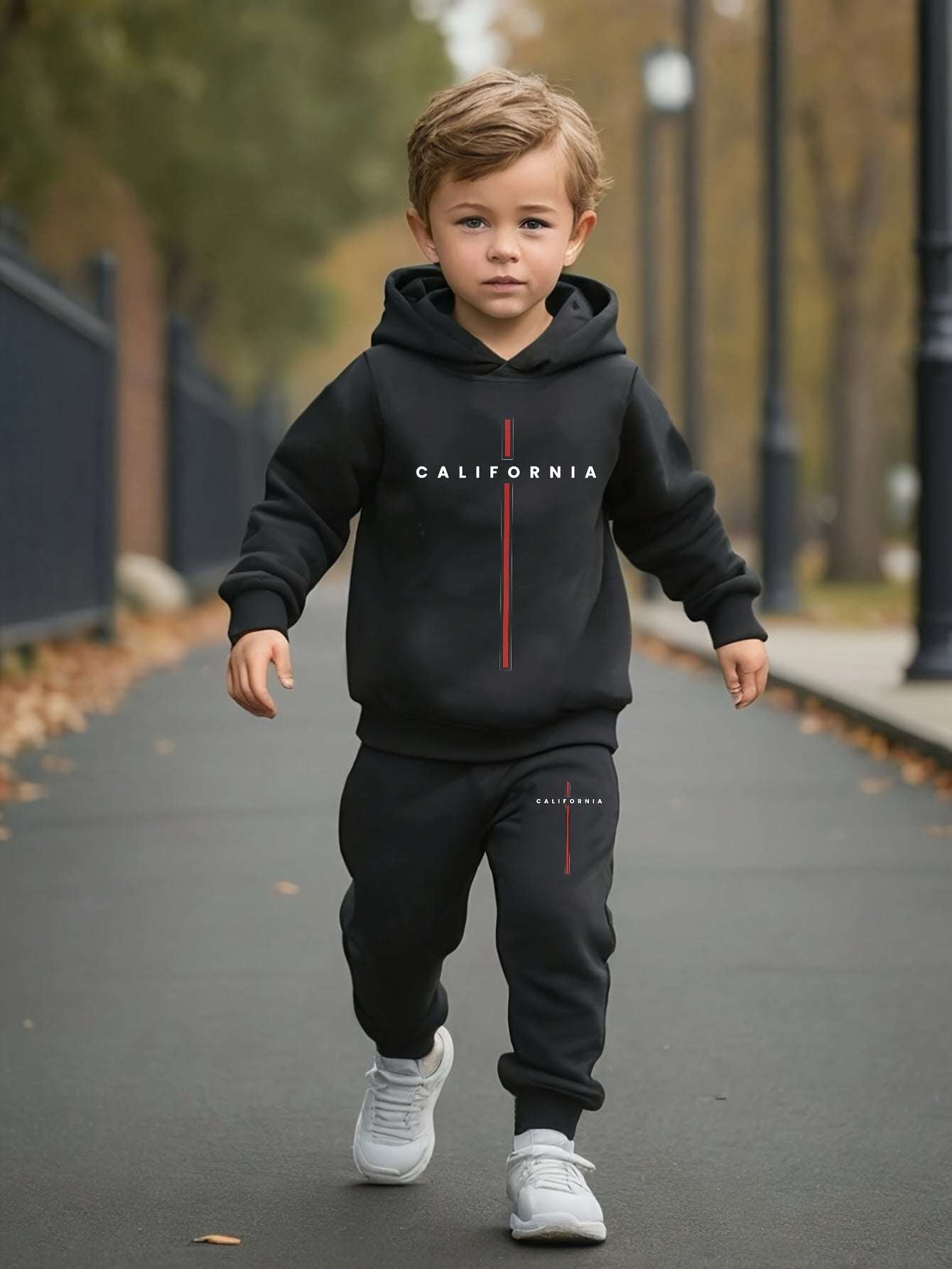 Boy wearing trendy California print outfit set with hooded sweatshirt and joggers, walking outdoors.