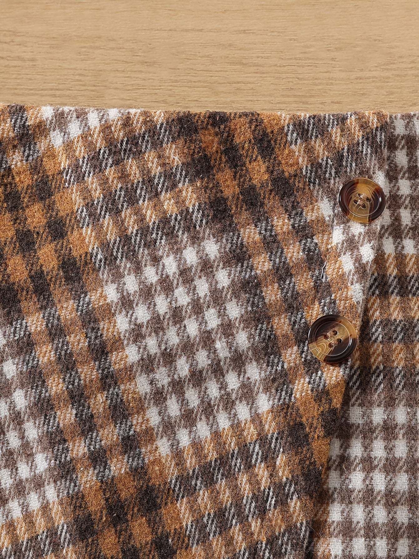 Close-up of chic checkered skirt in stylish two-piece set with button detail.