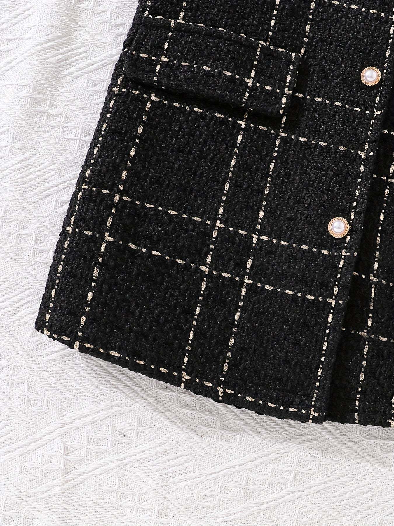 Close-up of trendy girls' outfit with a black and white checkered pattern, emphasizing cozy fall style.
