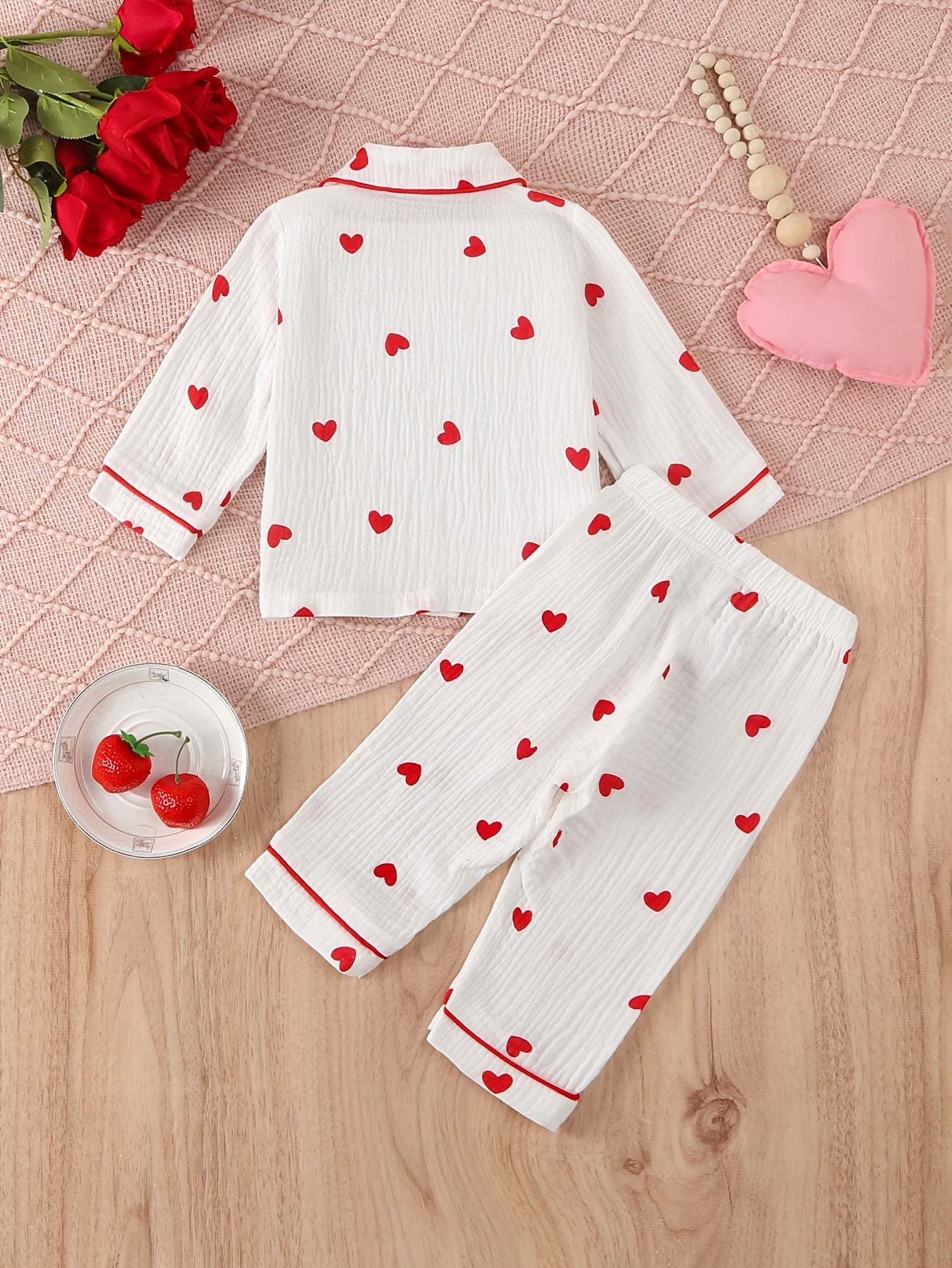 Adorable heart-patterned pajama set for girls on a wooden surface.