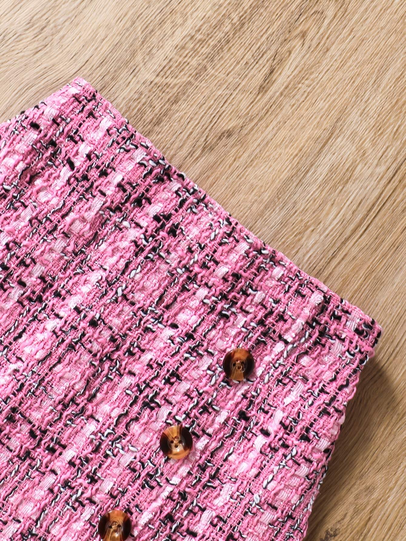 Close-up of pink tweed knit skirt with button details, part of 2-piece set.