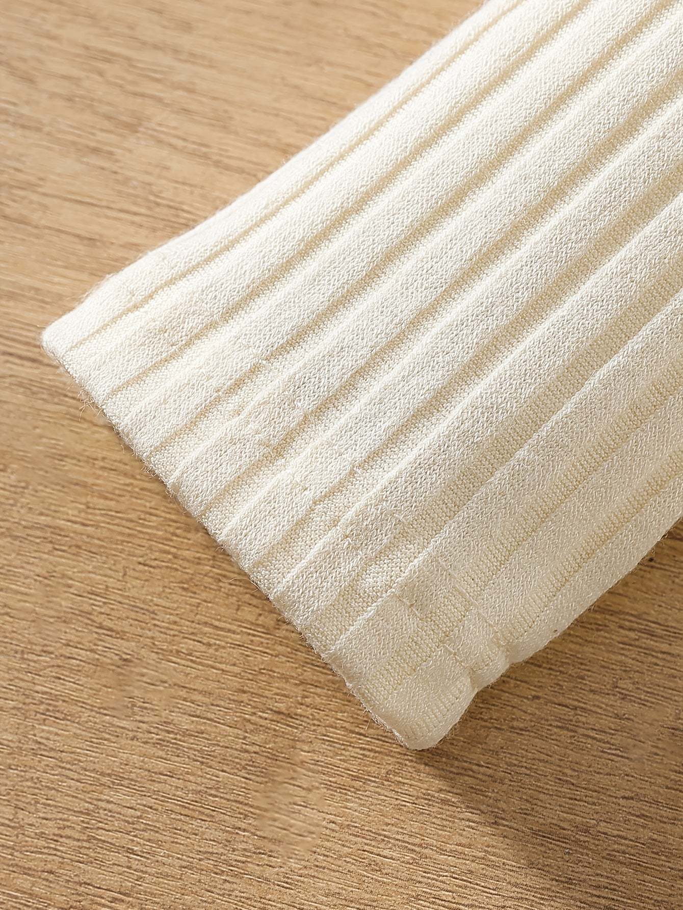 Close-up of cream knit fabric with ribbed texture, showcasing the soft and comfortable material of the stylish two-piece set.