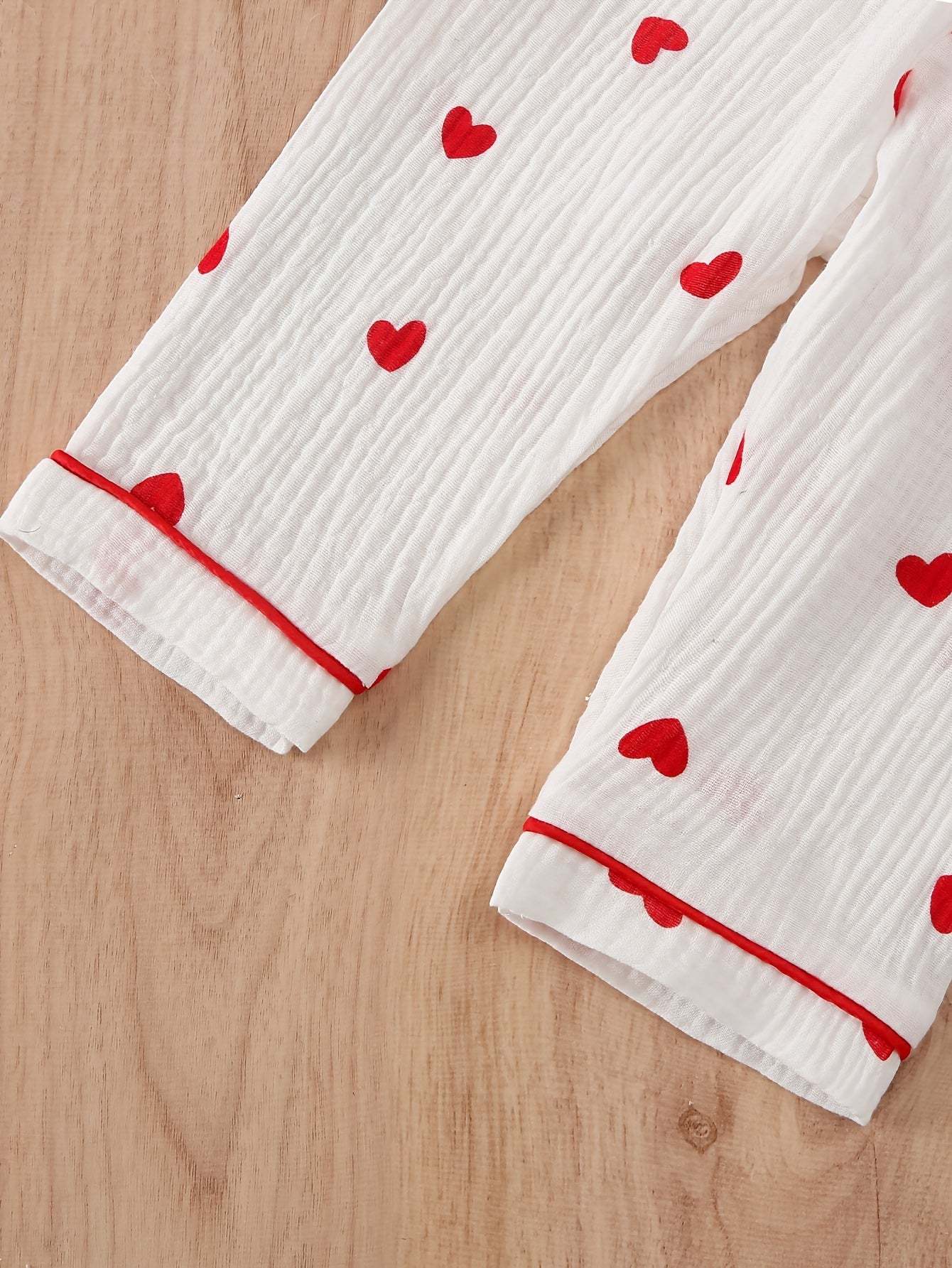 Adorable heart-patterned pajama set for girls with soft cotton fabric and vibrant red hearts.