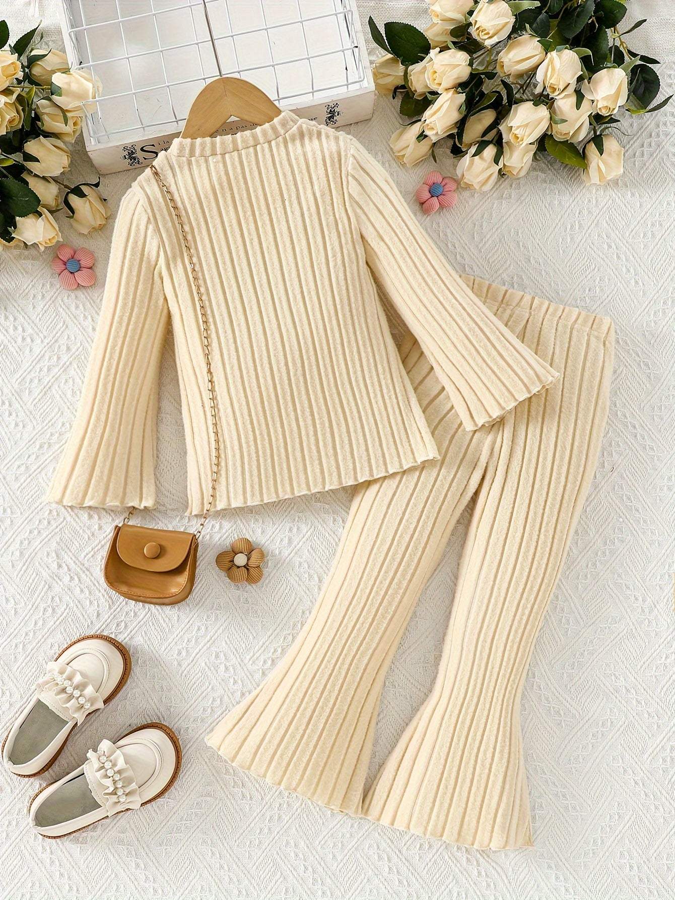 Stylish girls' outfit set with ribbed knit top and pants, surrounded by roses and accessories.