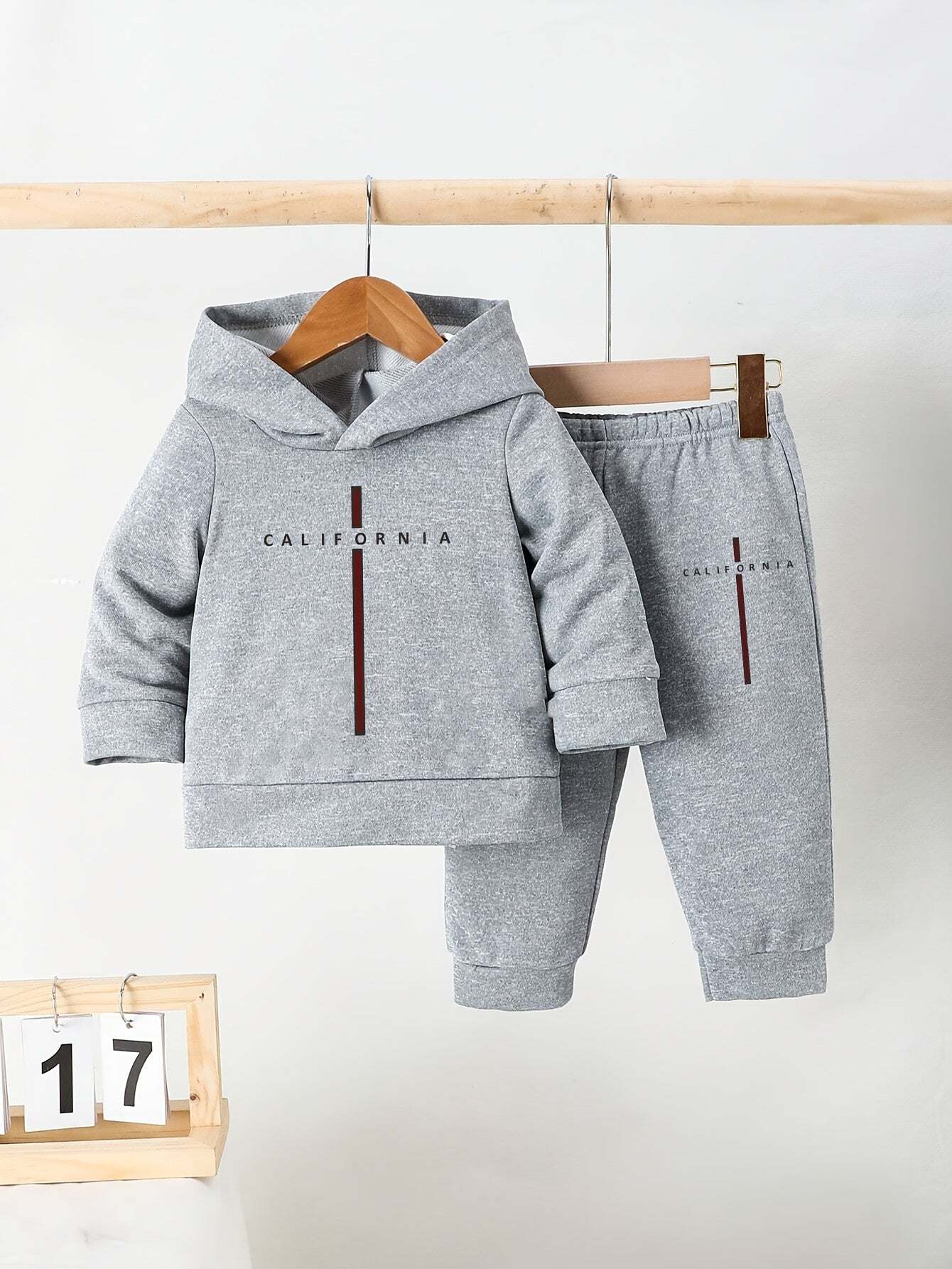 Trendy boys' California print outfit set with hooded sweatshirt and pants, displayed on hangers.