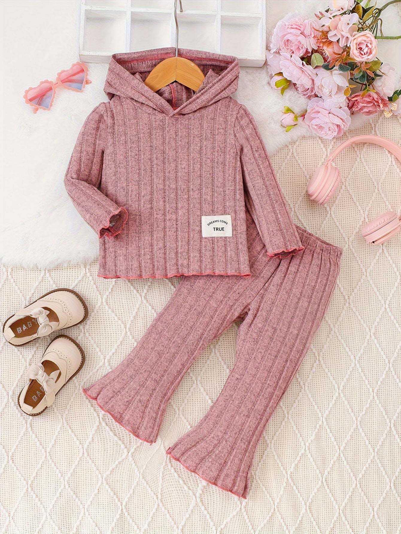 Pretty in pink 2-piece shirt and pants set for kids, ribbed texture, with flowers and headphones in background.