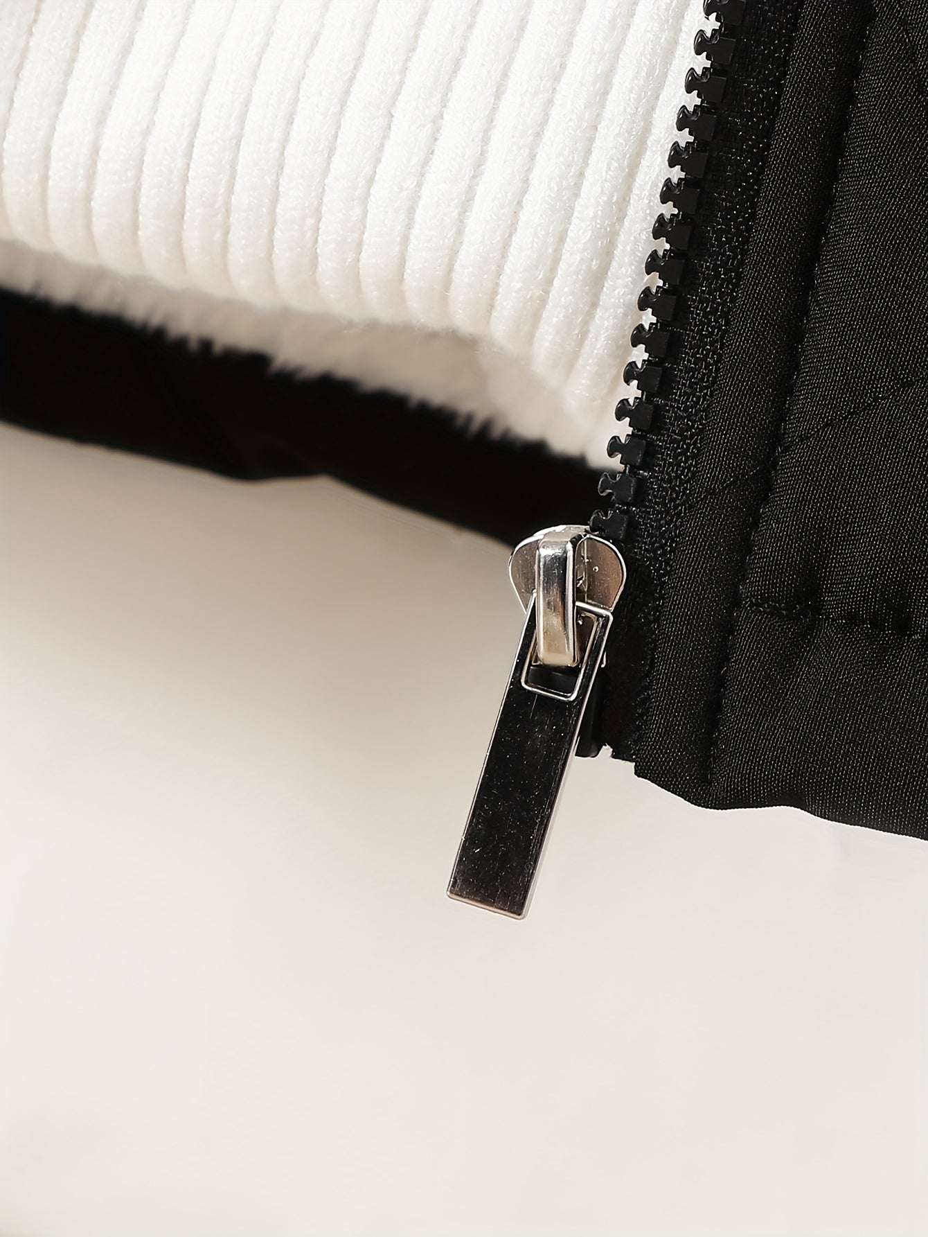 Close-up of a zipper on a chic velvet hooded jacket for infants and toddlers, emphasizing stylish and cozy layering.