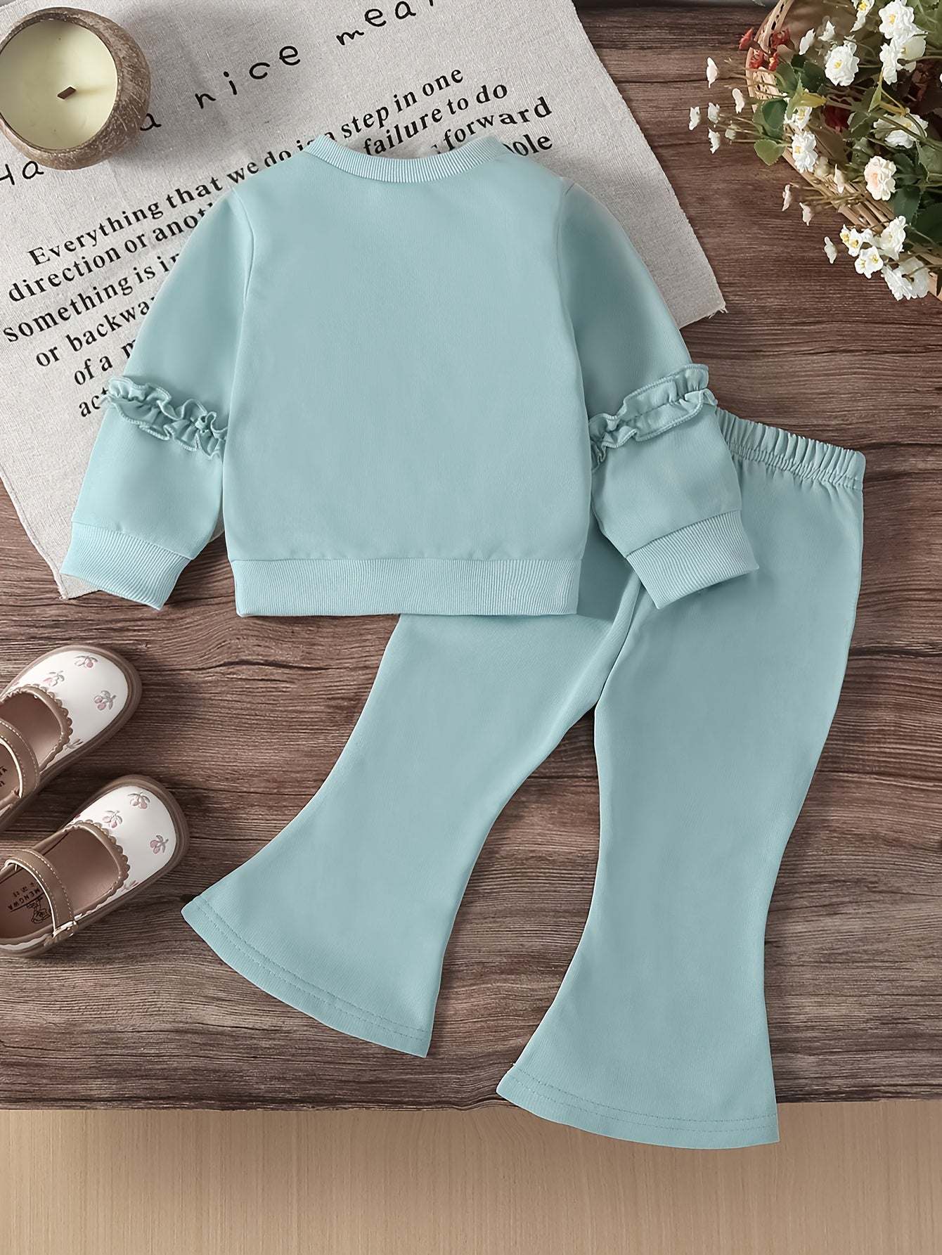 Trendy two-piece set for girls with matching light blue pants and top on a wooden surface.