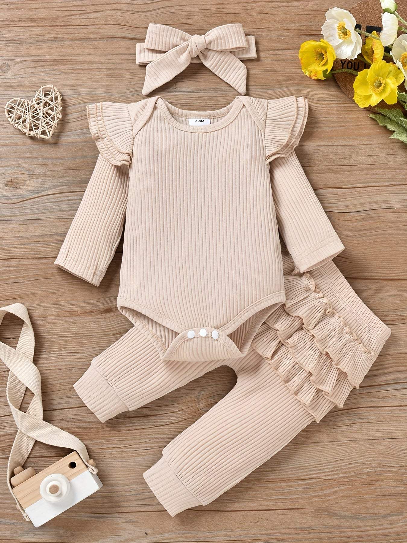 Charming trio 3-piece outfit set with headband for girls, featuring ruffled top, pants, and accessories on wooden background.